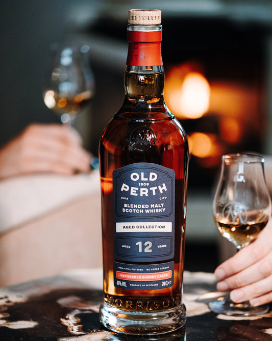 Bottle of Old Perth whisky with a glass on a table in a cozy setting