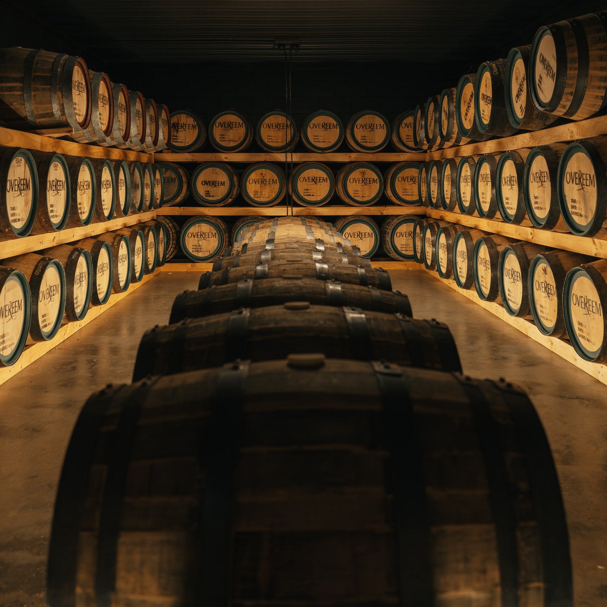 Row of Overeem barrels in a wine cellar with dim lighting.